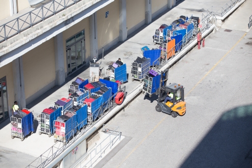 Forklifts loading baggage carts onto the ship.